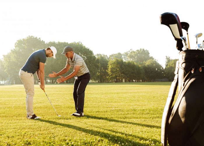 young-sportsman-practicing-golf-with-his-teacher